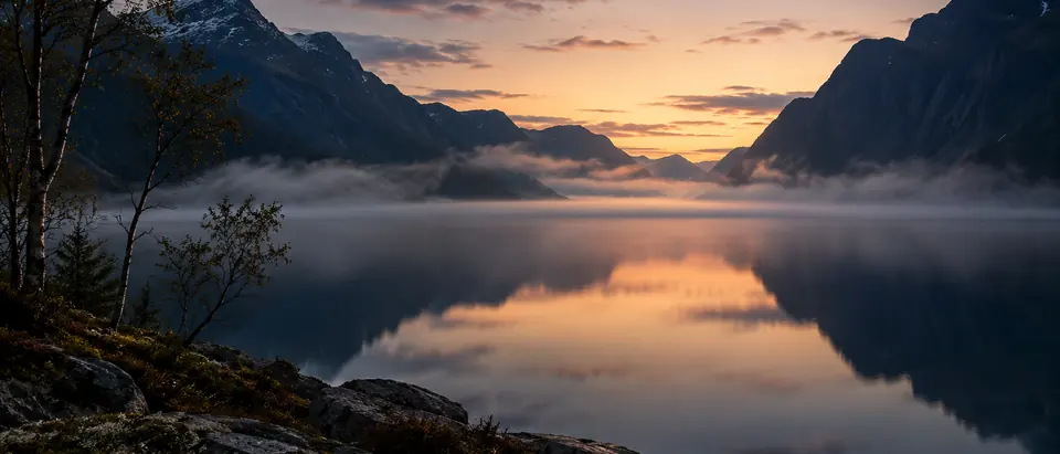 Fjord ved Bergen i morgengry med tåke over vannet og mørke fjell